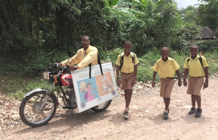 Kinder begleiten Motoradfahrer mit Schulmaterial